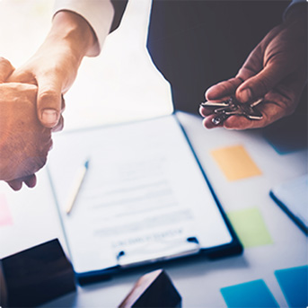 two people shaking hands over papers on table