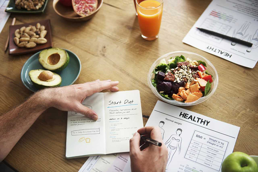 image of table with healthy food and man's hands planning diet